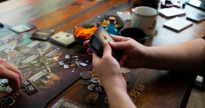 Joueur tenant des cartes au-dessus d'un plateau de jeu
