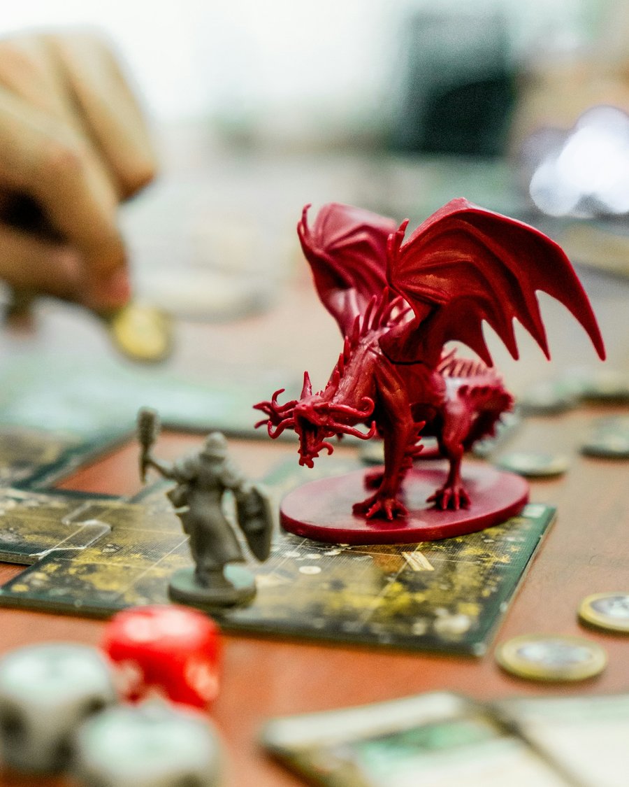 Figurine de dragon rouge face à un aventurier sur un plateau de jeu